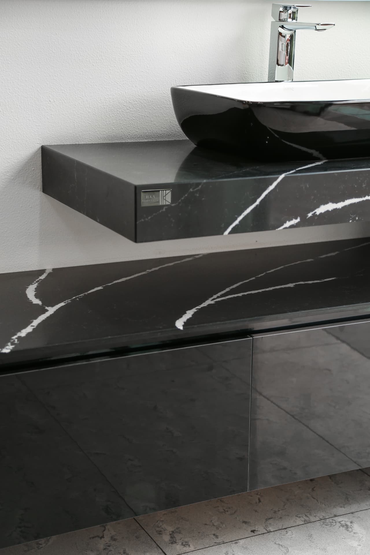 Floating black marble washbasin with ILKA's official plaque on its edge